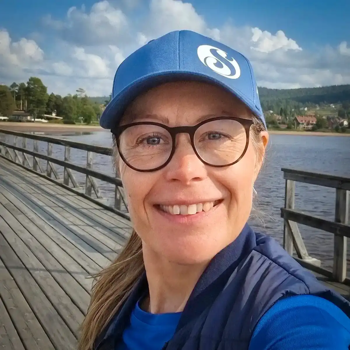 Sussi står på Långbryggan i Rättvik iförd blå keps och glasögon